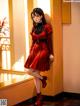 A woman in a red dress leaning against a window.